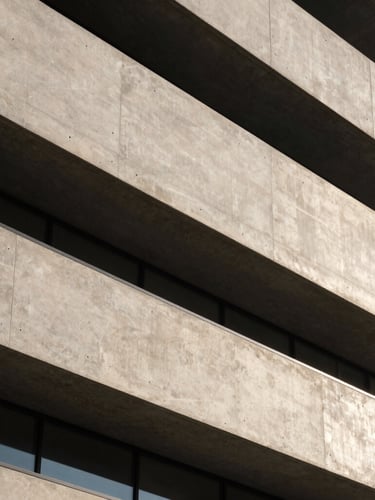 Abstract architectural detail of a modern concrete and steel facade, sharp morning daylight with deep shadows, high-contrast, elegant neutral tones, 35mm lens