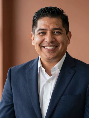Warm editorial portrait of a Hispanic lawyer smiling warmly in a bright El Monte office, soft natural window light, deep navy suit, terracotta background tones, shallow depth of field.