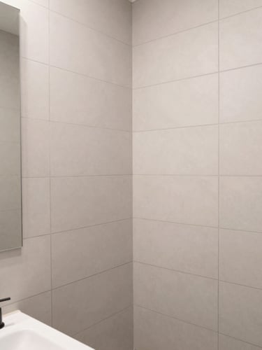 Crisp architectural close-up of a newly remodeled bathroom, flawless vertical tile joints, neutral gray grout, matte black fixtures, bright natural daylight