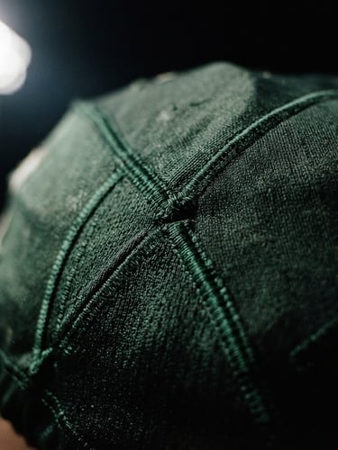 Close-up of a premium textured football jersey fabric with deep green stitching under dramatic stadium floodlight illumination, high-contrast 35mm film