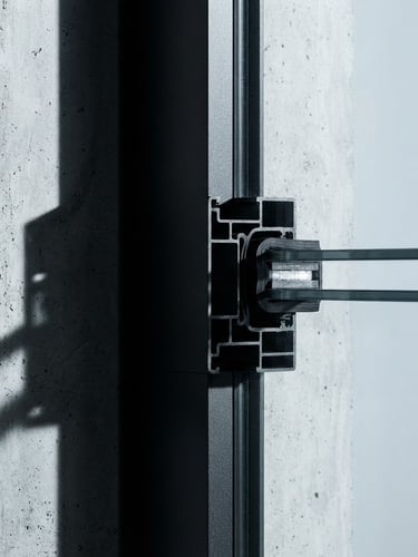 Orthographic technical shot of a matte black steel window frame profile, sharp geometric shadows, high-contrast crisp architectural lighting, cool metallic tones.