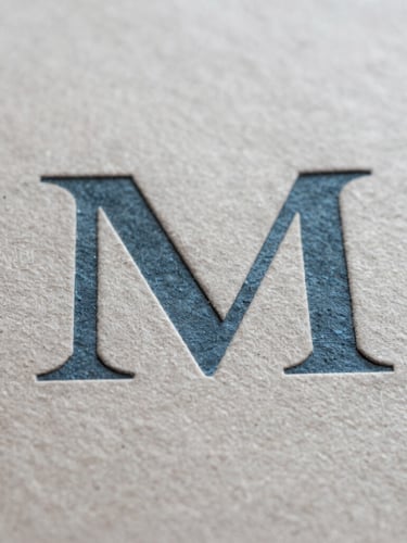 Macro close-up of textured paper and debossed slate blue typography, soft natural light