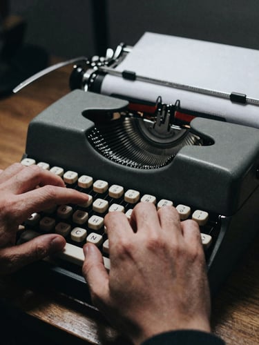 Environmental close-up of a journalist's hands typing on a vintage mechanical typewriter, high-contrast side-lighting, desaturated tones, grainy 35mm film style.