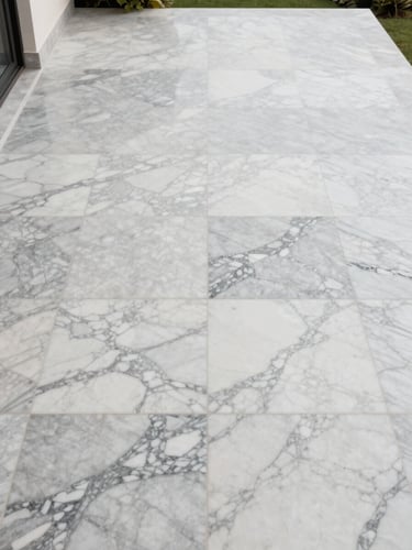 Overhead orthographic view of a private villa terrace, large-format Calacatta marble slabs laid in book-matched pairs, veins symmetrical across the full floor plane, bright overcast daylight, no furniture visible — pure material at scale