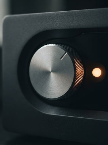 Macro close-up of a machined aluminum dial on a dark obsidian hardware device, soft orange indicator light glowing, low-key side window lighting, shallow depth of field
