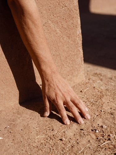Rustic architectural details of Finca Akasha, hands touching dry earth, warm editorial photography, earthy terracotta tones, 35mm film.