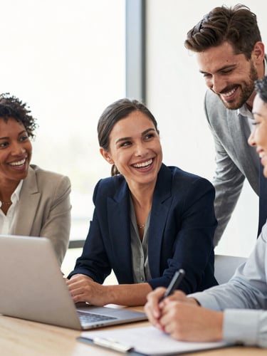 Candid portrait of a diverse team of corporate professionals smiling and discussing work around a table, bright natural light, genuine laughter, warm modern office setting.