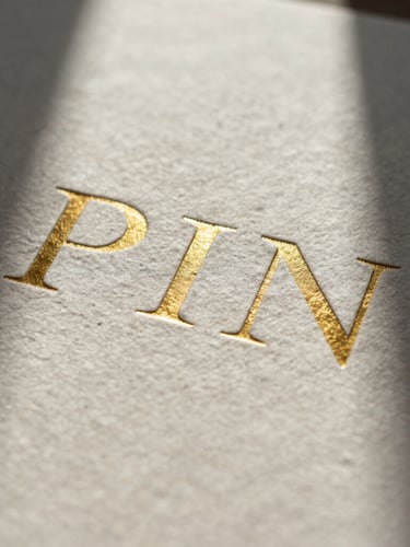 Macro close-up of heavy textured cotton paper stock with debossed gold foil typography, architectural shadows cast across the surface, minimalist composition