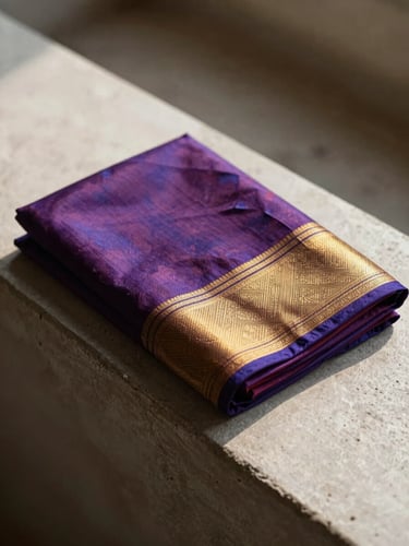 Warm editorial photography of a silk saree neatly folded on a minimalist concrete ledge, showing rich contrasting jewel tones, high-contrast natural sunlight, 35mm.