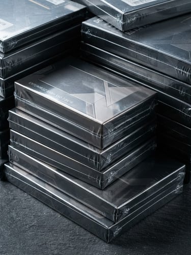 Macro shot of sealed retail boxes of enterprise NVMe SSDs and RAM modules stacked on a clean slate gray surface under cool studio lighting