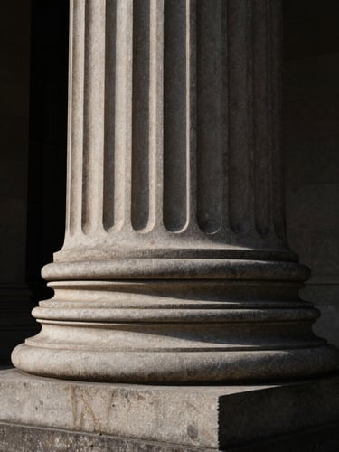 Wide-angle architectural detail of a classical stone column bathed in dramatic low-key natural light, deep shadows, high-contrast texture.