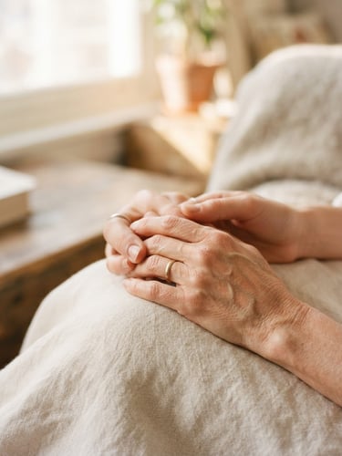 Close-up detail of hands holding gently, warm domestic setting with soft morning daylight filtering in, shallow depth of field, warm editorial photography