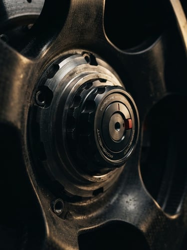 Cinematic extreme macro close-up of a machined billet-aluminum wheel center lock, dramatic low-key studio lighting with golden-hour rim highlights, 35mm anamorphic.