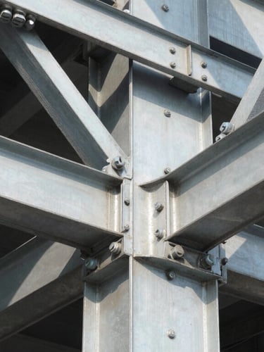 Close-up architectural detail of a heavy steel structural joint with massive bolts, industrial precision, crisp daylight, deep shadows