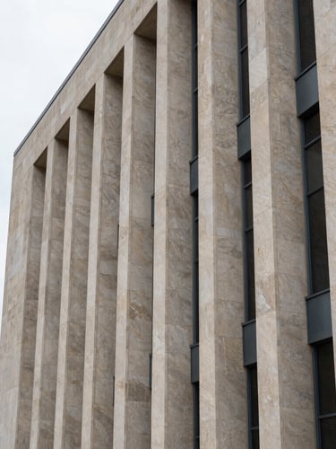 Crisp architectural detail of a modern limestone and steel courthouse facade under overcast daylight, sharp vertical lines, generous negative space on the left