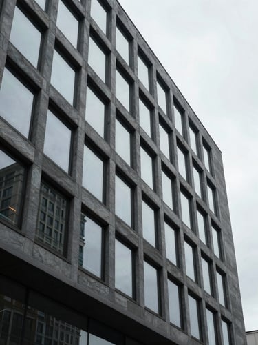 Stark architectural perspective of a modern corporate office building facade, cool overcast daylight, sharp geometric lines, slate gray tones.