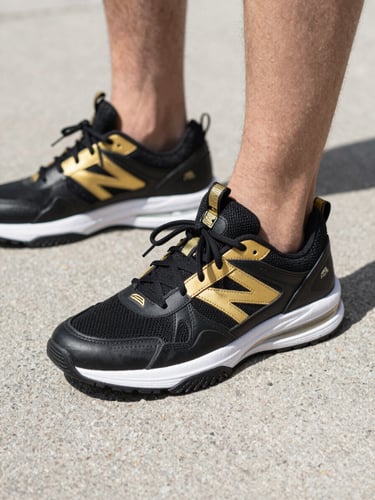 Close-up of premium modern black and gold athletic sneakers on urban pavement, sharp daylight, high contrast streetwear photography, 35mm lens
