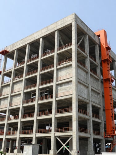 Wide-angle architectural perspective of a massive concrete industrial facility in Bangladesh, bright natural daylight, clean structural steel framing, safety-orange accents, sharp focus