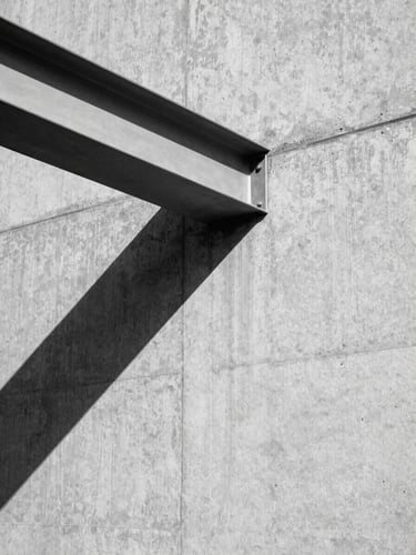 High-contrast black-and-white architectural photograph of a raw concrete wall meeting a sharp steel beam at a 45-degree angle, hard directional sunlight casting a razor-sharp shadow, orthographic composition.