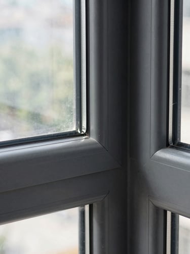 Sharp architectural close-up of a modern anthracite aluminum window frame joint, perfect seal visible, crisp natural daylight, realistic textures, 35mm lens