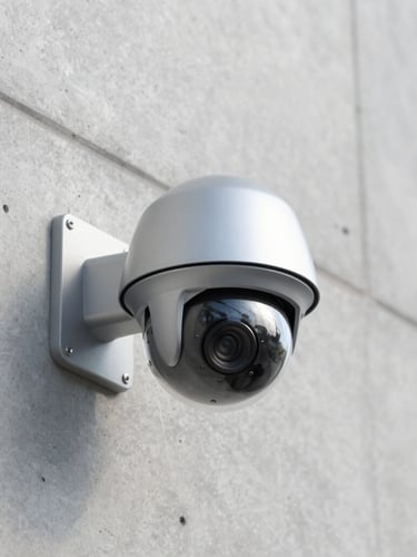 Sharp architectural photography of a modern high-end dome security camera neatly mounted on a clean concrete wall under bright natural daylight, cool slate tones, zero visible wires, professional depth of field.