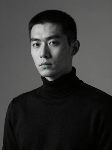 Low-contrast professional portrait of ARIY in a neutral-toned studio setting, soft key light, minimalist black turtleneck, looking slightly off-camera, sharp focus
