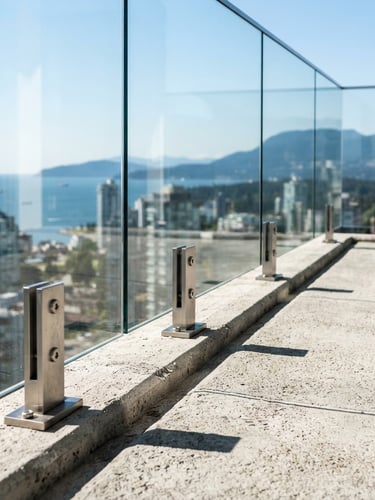 Crisp architectural photography of a minimalist glass guardrail with brushed steel connectors on a high-end concrete balcony, sharp high-contrast shadows, cool daylight, 50mm lens