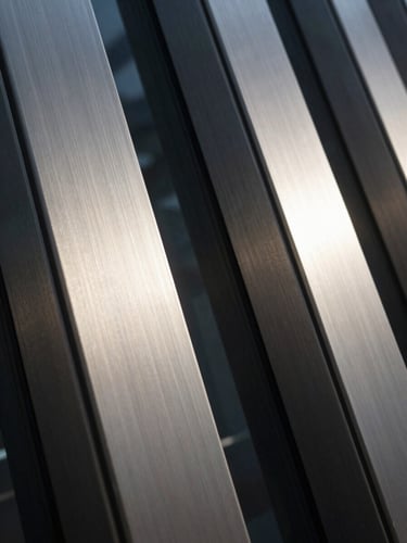 Extreme close-up of premium physical materials, brushed steel and dark architectural glass with sharp vertical lines, low-key chiaroscuro lighting, cool silver tones.