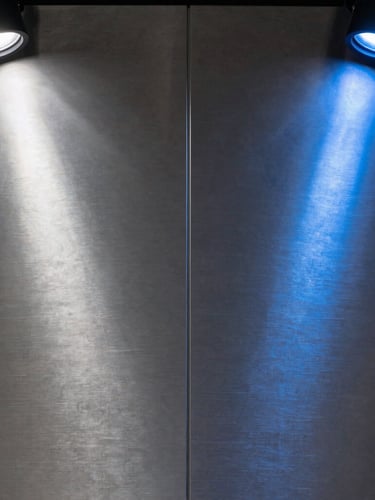 Extreme close-up of premium brushed titanium paneling with razor-thin vertical joints under cold silver and cobalt blue spotlights.