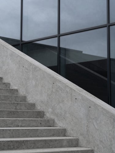 Stark, high-contrast architectural detail of concrete stairs meeting a glass wall, sharp angles, cool overcast daylight, minimalist composition, 35mm