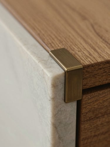 Macro close-up of a chiselled marble edge meeting a seamlessly inset brushed bronze fitting, soft natural side-light, shallow depth of field