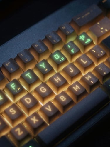 Macro close-up of a high-contrast mechanical keyboard in a dark room, glowing amber and green terminal screen reflections on the keycaps, 35mm