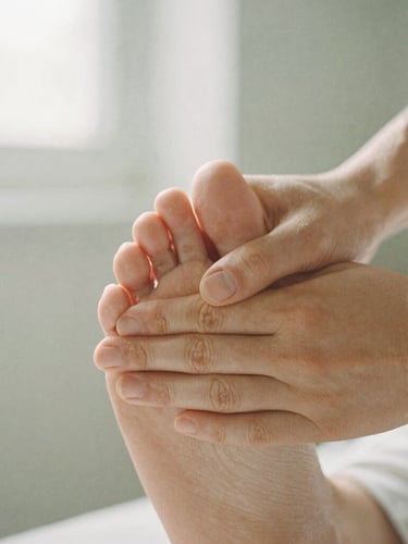 Macro shot of hands applying precise pressure to a foot, soft diffused natural daylight, shallow depth of field, organic linen texture, 35mm film feel