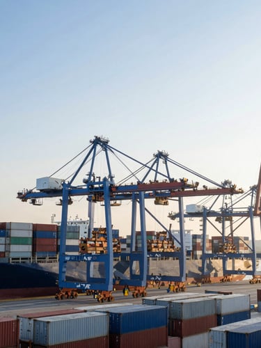 Wide environmental shot of a busy modern container port at sunrise, cargo cranes loading container ships, cool blue and white tones.