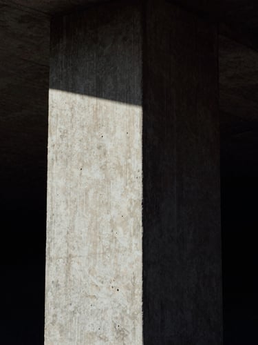 High-contrast portrait of a brutalist concrete column under dramatic low-key natural light, deep shadows, raw concrete texture, medium-format film grain, dark atmospheric photography