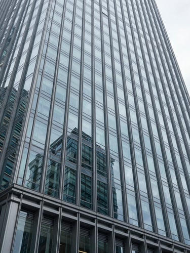 Wide-angle architectural crop of modern glass-and-steel skyscraper facade reflecting cool diffused daylight, sharp focus, 35mm