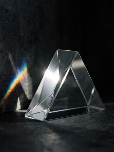 Extreme close-up of sharp directional light reflecting off a flawless glass prism, deep shadows, minimalist architectural background, 35mm