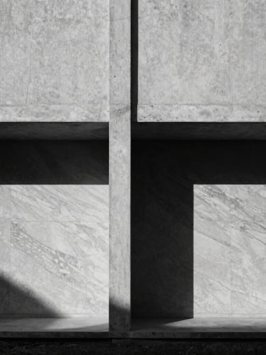 Symmetrical medium-format composition of a minimalist raw concrete villa facade, a single concrete column casting a deep shadow against textured marble, dramatic late afternoon sun.