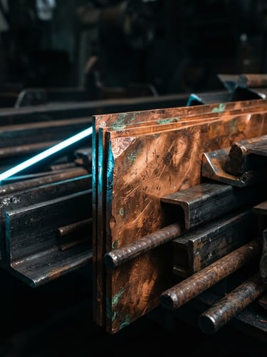 High-contrast macro shot of raw copper alloy sheets and industrial metal bars under dramatic low-key lighting.