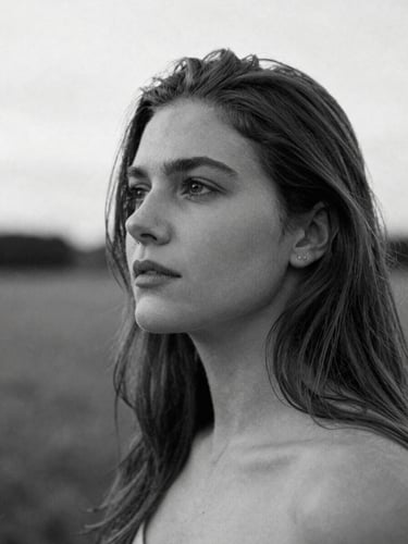 Natural portrait of Leila Krüger in a contemplative setting, soft diffused daylight, high-contrast black and white, shallow depth of field, 35mm film grain, minimalist editorial photography