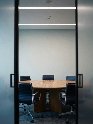 A quiet executive meeting room in London, soft corporate interior lighting, minimalist wooden table, cool-toned editorial style, 35mm.