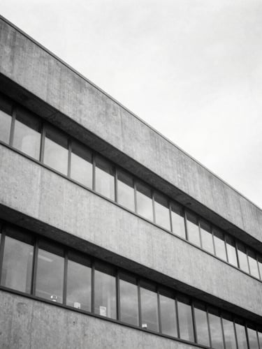 A sharp architectural black and white photograph of a modern medical research facility facade, clean concrete angles, soft overcast daylight, 35mm lens.