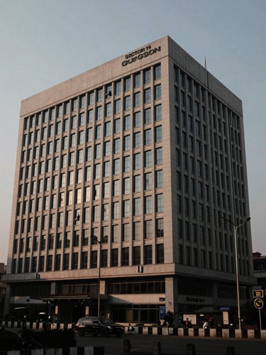 Wide photojournalistic shot of the exterior of a modern, authoritative office building in Sector 14, Gurgaon, India, at dusk. High contrast, natural light, desaturated tones, with a focus on the architecture and surrounding urban environment.