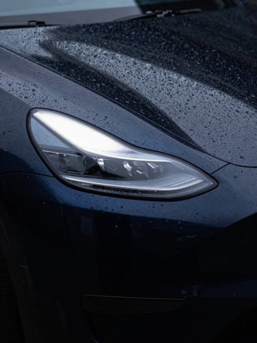 Extreme close-up of water beading flawlessly on a deep obsidian black ceramic-coated electric vehicle, sharp LED light bar reflections, dark studio lighting, 85mm lens