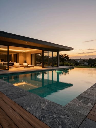Wide-angle architectural twilight shot of a seamless indoor-outdoor transition, zero-edge pool reflecting warm landscape lighting, slate and teak materials, 35mm