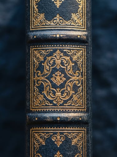 Macro photograph of a prestigious leather-bound book spine with gold foil lettering, warm side-lighting on rich navy linen texture, shallow depth of field