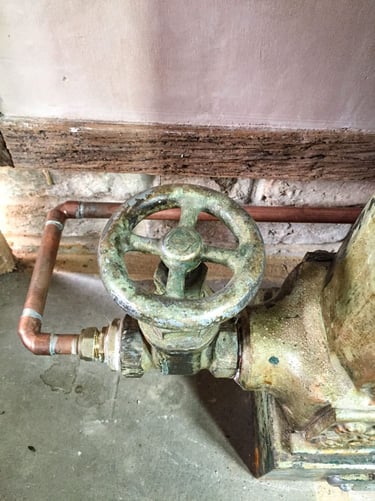 Close-up on a painted radiator valve and a new copper pipe on antique plaster wall
