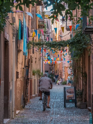 Man riding a bicycle in a cobblestone street in Bosa, Sardinia