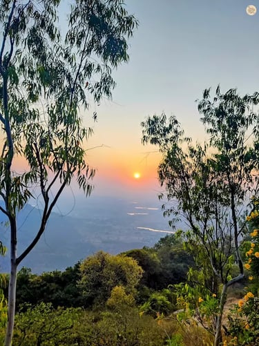 Beautiful sunset at the horizon as seen from Nandi Hills near Bengaluru, casting golden light over misty valleys and hilltops