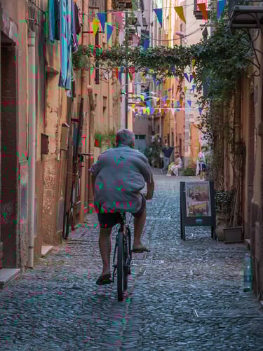 Man riding a bicycle in a cobblestone street in Bosa, Sardinia